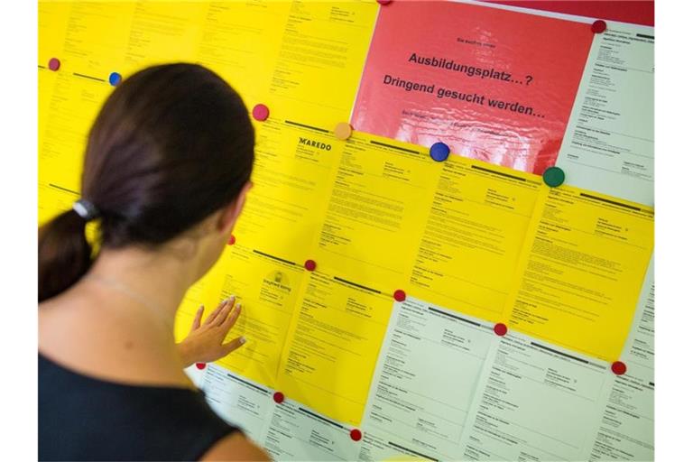 Eine junge Frau blickt auf eine Aushängewand mit Zetteln für freie Ausbildungsstellen. Foto: picture alliance / Christoph Schmidt/dpa/Archivbild