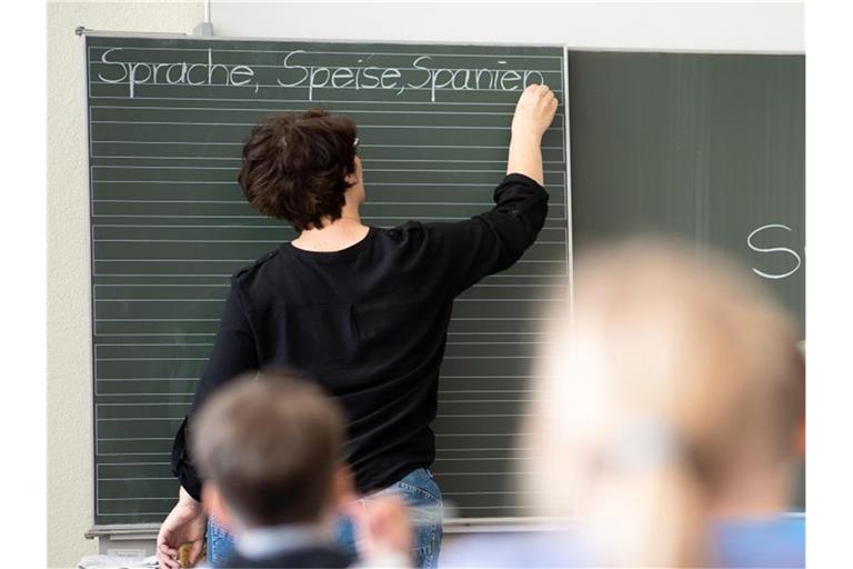 Eine Lehrerin in Baden-Württemberg schreibt in einer Schule an eine Tafel. Foto: Sebastian Gollnow/dpa/Symbolbild