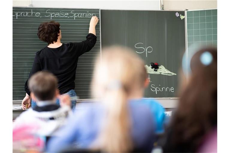 Eine Lehrerin schreibt in einer Schule an die Tafel. Foto: Sebastian Gollnow/dpa/Symbolbild