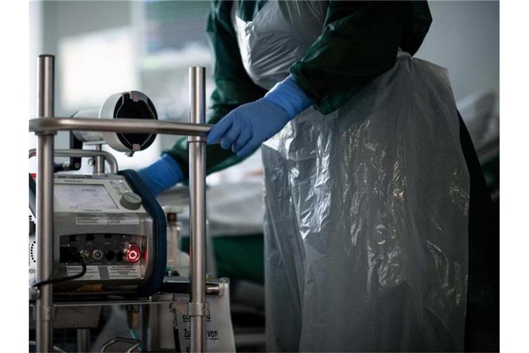 Eine Mitarbeiterin der Pflege steht in einem Zimmer einer Corona-Intensivstation. Foto: Fabian Strauch/dpa/Illustration