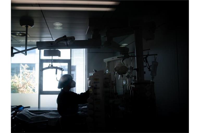 Eine Mitarbeiterin der Pflege steht in einem Zimmer einer Corona-Intensivstation. Foto: Fabian Strauch/dpa/Illustration