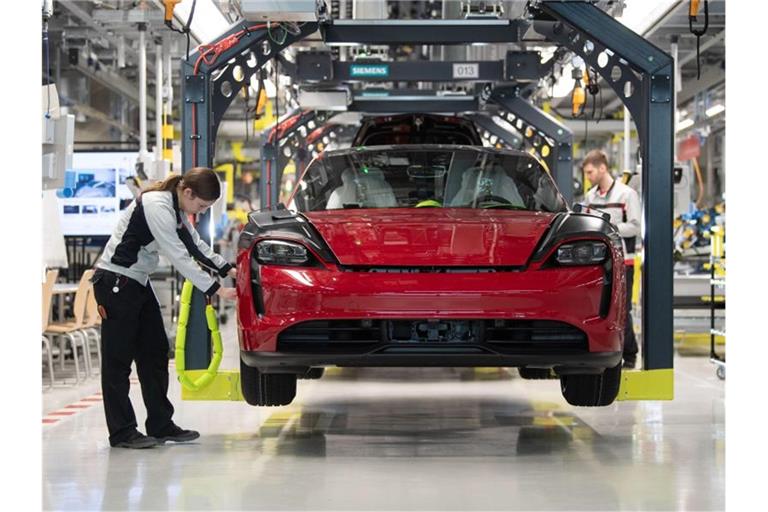 Eine Mitarbeiterin der Porsche AG kontrolliert in der Produktion einen Taycan. Foto: Marijan Murat/dpa/Symbolbild