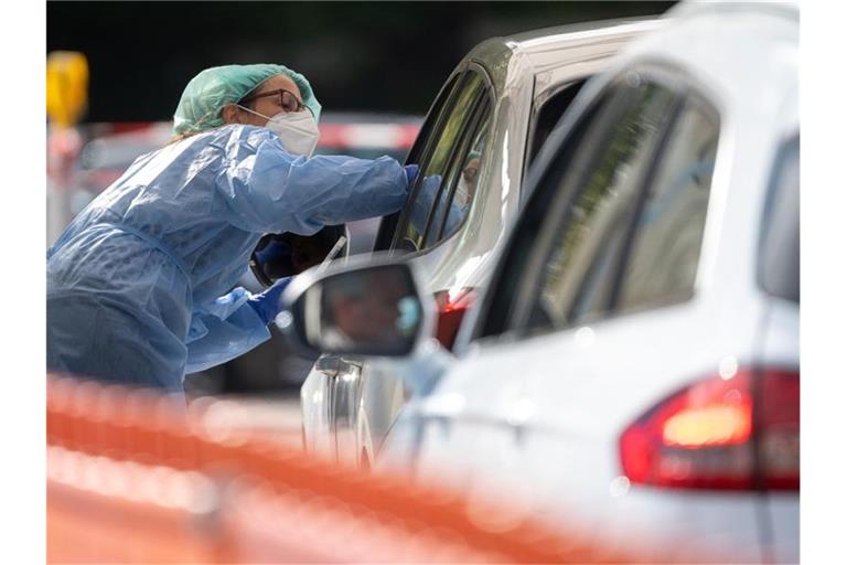 Eine Mitarbeiterin im Landkreis Esslingen macht im Corona-Abstrich-Zentrum bei einem Autofahrer einen Abstrich. Foto: Sebastian Gollnow/dpa