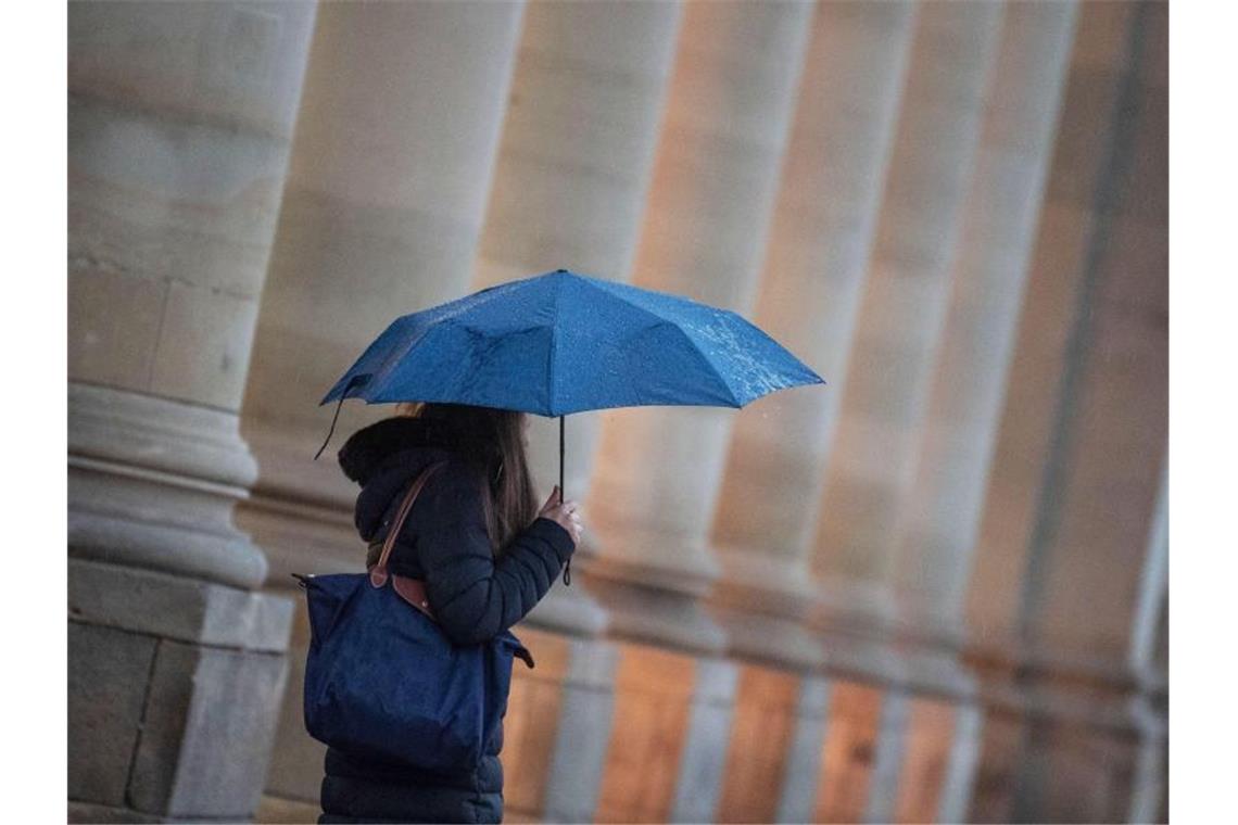 Wolken, Regen und Wind am Pfingstwochenende erwartet Eine Passantin geht bei Regen durch die Stadt. Foto: Marijan Murat/dpa/Symbolbild