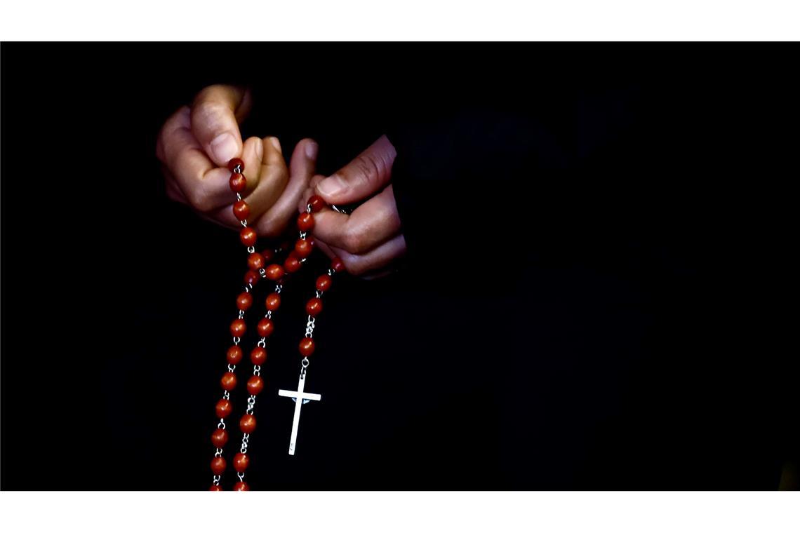 Eine Person hält einen Rosenkranz bei einem Gebet auf dem Petersplatz für die Gesundheit des Papstes.