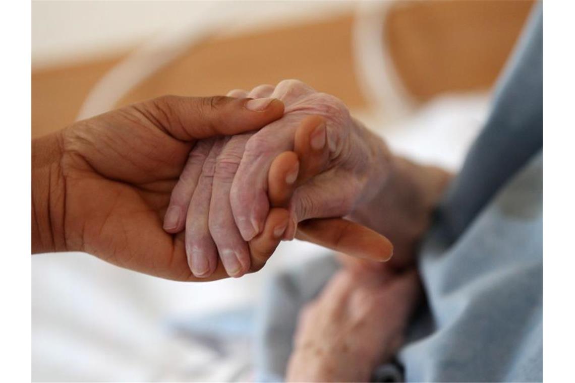 108-Jährige geimpft: „Hoffentlich hört Seuche bald auf“ Eine Pflegerin hält im Altenheim die Hand einer Bewohnerin. Foto: Oliver Berg/dpa/Symbolbild