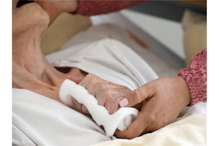 Eine Pflegeschwester hält die Hand einer alten Heimbewohnerin. Foto: Bodo Schackow/dpa-Zentralbild/dpa/Symbolbild