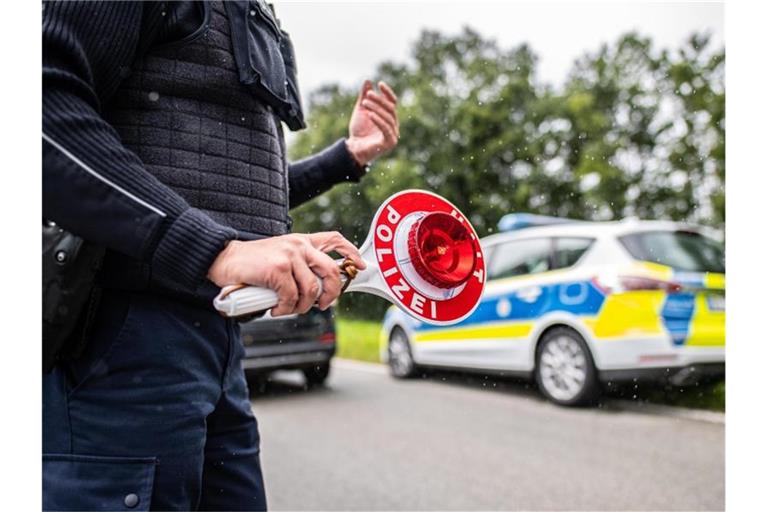 Eine Polizistin steht mit einer Winkerkelle in der Hand auf der Straße. Foto: Guido Kirchner/dpa/Symbolbild