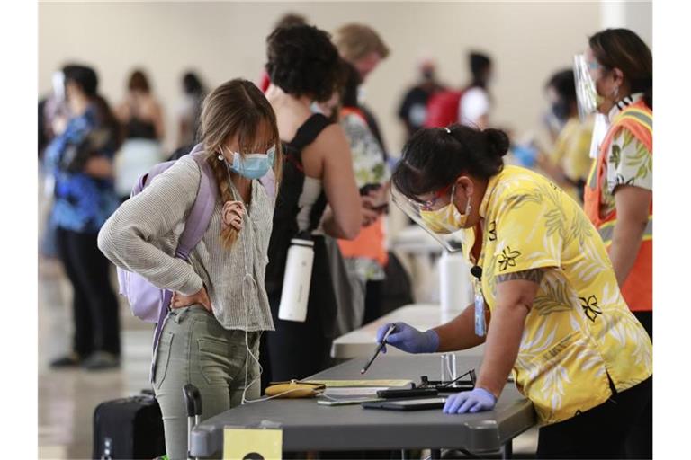 Eine Reisende auf Hawaii lässt sich vor einem Test beraten. Foto: Marco Garcia/AP/dpa