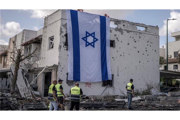 Eine riesige israelische Fahne hängt vom Dach eines beschädigten Gebäudes in Kiriat Bialik.