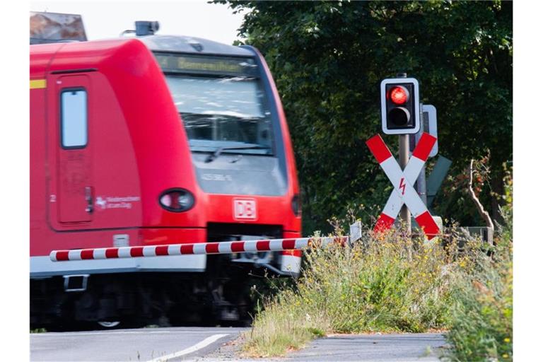 Eine S-Bahn der Deutschen Bahn (DB) fährt an einem Bahnübergang mit einer roten Ampel vorbei. Foto: Julian Stratenschulte/dpa