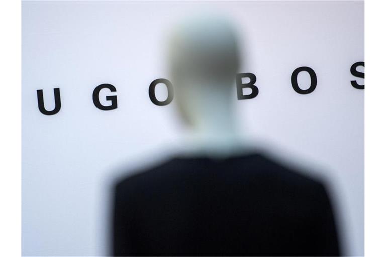 Eine Schaufensterpuppe steht vor dem Schriftzug "Hugo Boss". Foto: Sebastian Gollnow/dpa/Archivbild