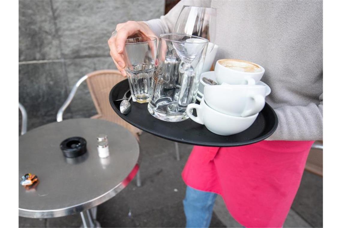 Eine Servicekraft räumt die Tische in einem Café ab. Foto: Sebastian Gollnow/dpa/Symbolbild