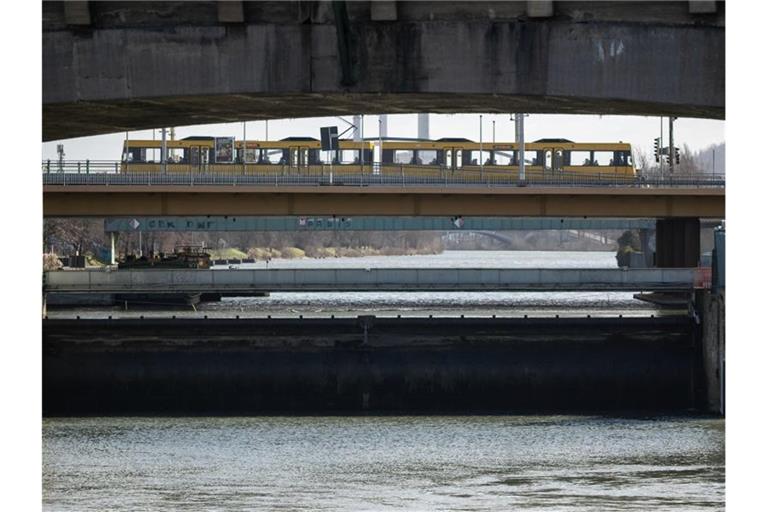 Eine Stadtbahn fährt über eine Brücke, darunter sind der Neckar und das Wehr der Staustufe Cannstatt zu sehen. Foto: Marijan Murat/dpa