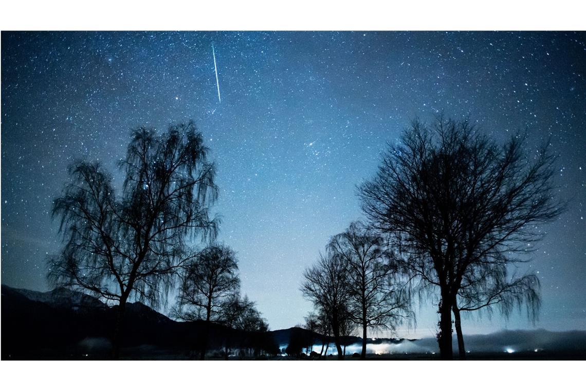 Eine Sternschnuppe ist während des Geminiden-Meteorenstroms im bayerischen Kochel am See zu sehen.