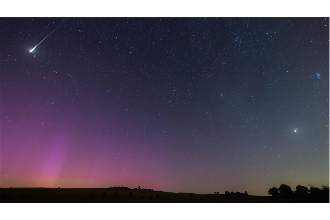 Eine Sternschnuppe vor farblich erleuchtetem Himmel: ein besonderes Schauspiel.