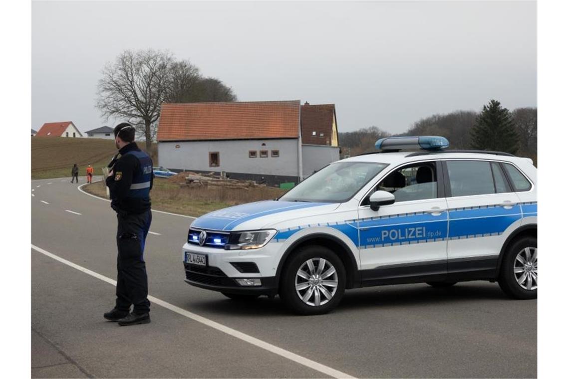 Nach Fund zweier Leichen: Fahndung nach tatverdächtigem Sohn Eine Straße wird mit einem Einsatzfahrzeug der Polizei abgesperrt. Foto: Harald Tittel/dpa