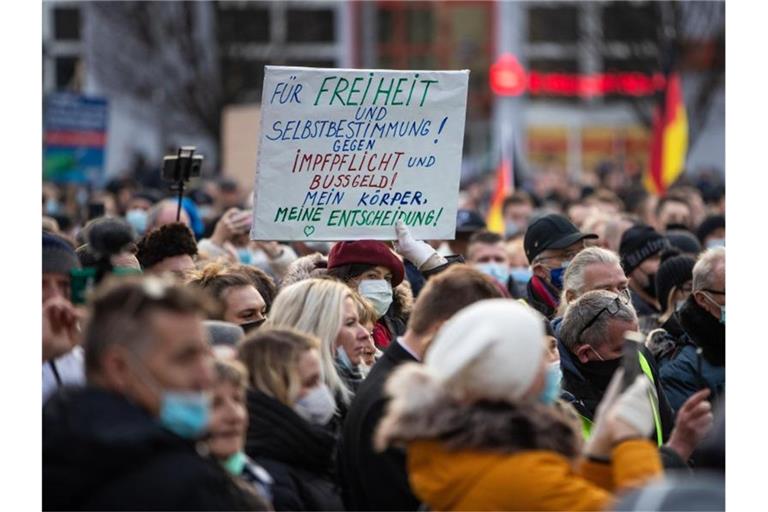 Eine Teilnehmerin einer Demonstration gegen die Corona-Maßnahmen hebt ein Transparent mit der Aufschrift "Für Freiheit und Selbstbestimmung! Gegen Impflicht und Bussgeld! Mein Körper, meine Entscheidung!" in die Höhe. Foto: Christoph Schmidt/dpa/Archivbild