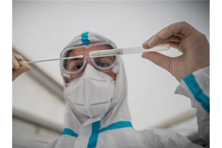 Eine Virologin steckt ein Wattestäbchen in ein Plastikröhrchen. Foto: Michael Kappeler/dpa/Symbolbild