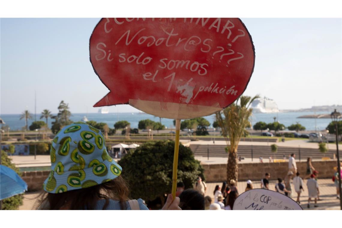 Einheimische auf Mallorca halten ein Schild, auf dem steht: "Verschmutzen? Wir??? Wo wir nur 1,2 (Millionen) Einwohner sind."