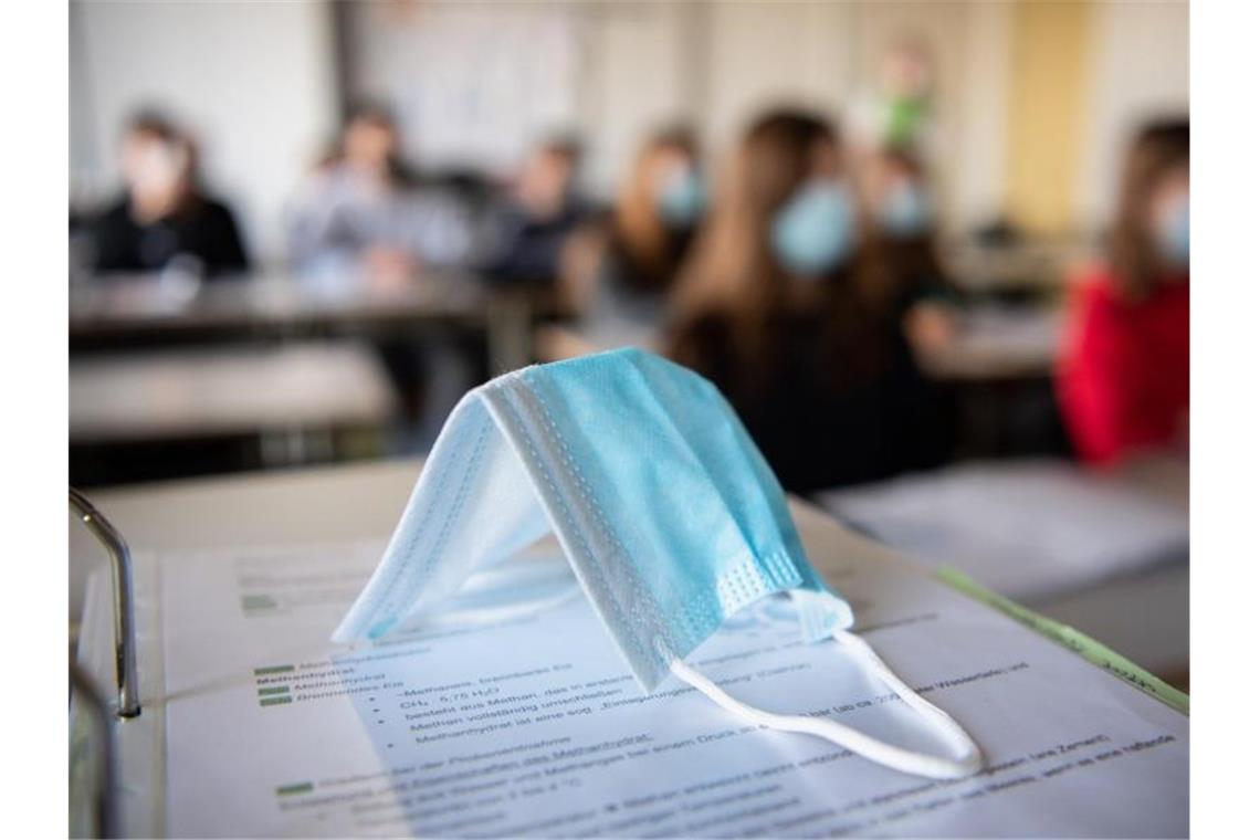 Schulschließung in Hotspots im Gespräch Ein Mund-Nasen-Schutz liegt im Unterricht auf Unterlagen. Foto: Matthias Balk/dpa/Symbolbild