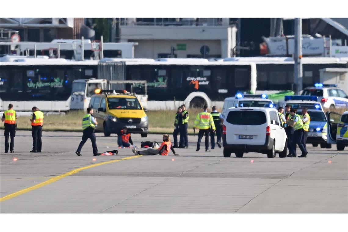 Einsatzfahrzeuge von Polizei, Feuerwehr und Flughafen-Sicherheit stehen auf dem Vorfeld des Frankfurter Flughafens, wo sich zwei Aktivisten (M) festgeklebt haben.