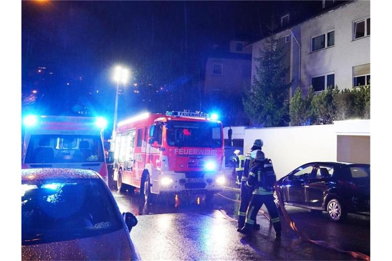 Einsatzkräfte der Feuerwehr, Rettungskräfte und Polizei stehen für Löscharbeiten vor dem Haus. Foto: Andreas Rosar/dpa