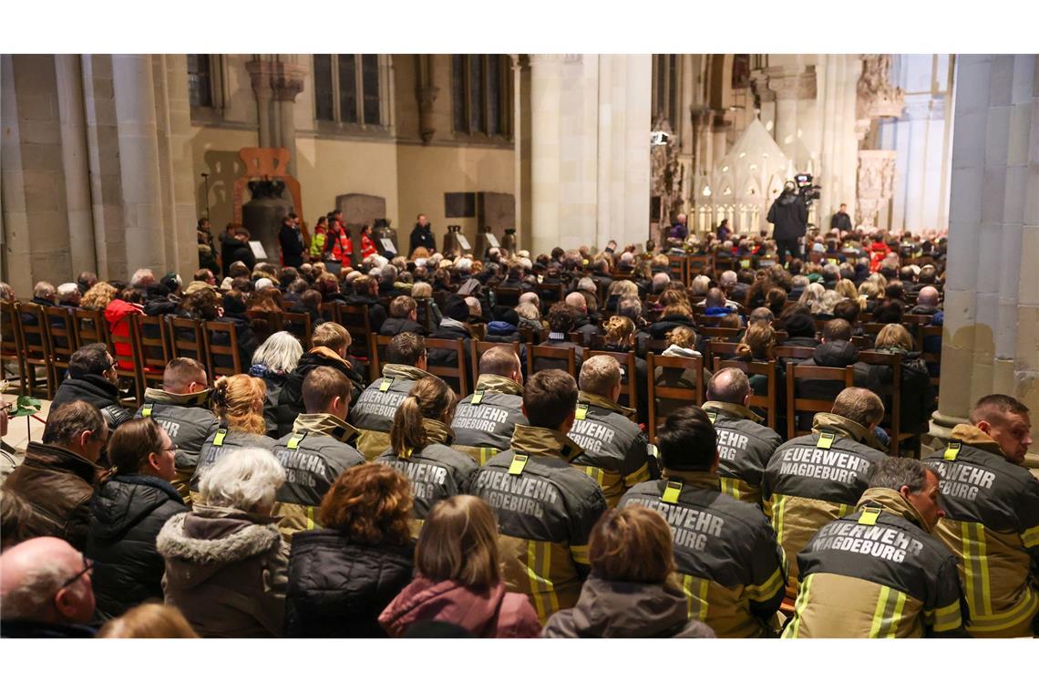 Einsatzkräfte der Feuerwehr sitzen in der Gedenkveranstaltung im Magdeburger Dom.