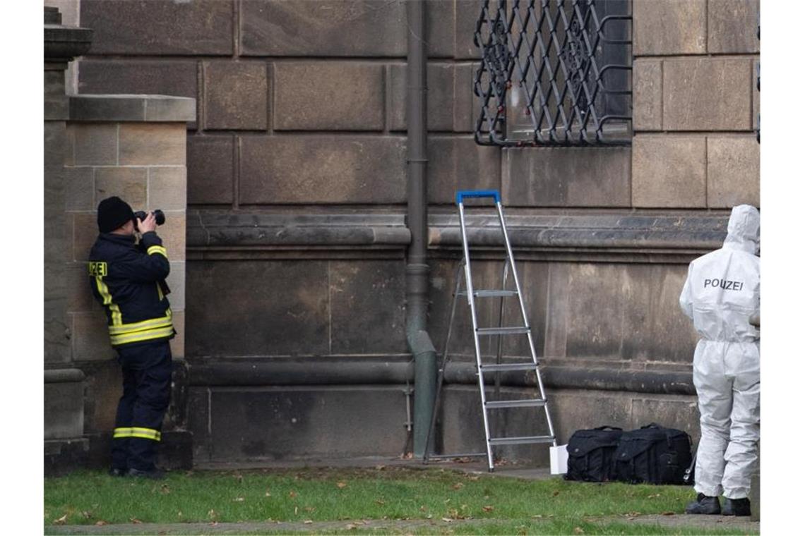 Nach Juwelendiebstahl: Verdächtige aus Clan-Milieu gefasst Einsatzkräfte der Polizei stehen im Bärengarten neben dem durchtrennten Gitterfenster des Grünen Gewölbes am Residenzschloss. Knapp ein Jahr nach dem Kunstraub im Dresdner Grünen Gewölbe hat die Polizei in Berlin drei Tatverdächtige festgenommen. Foto: Sebastian Kahnert/dpa-Zentralbild/dpa