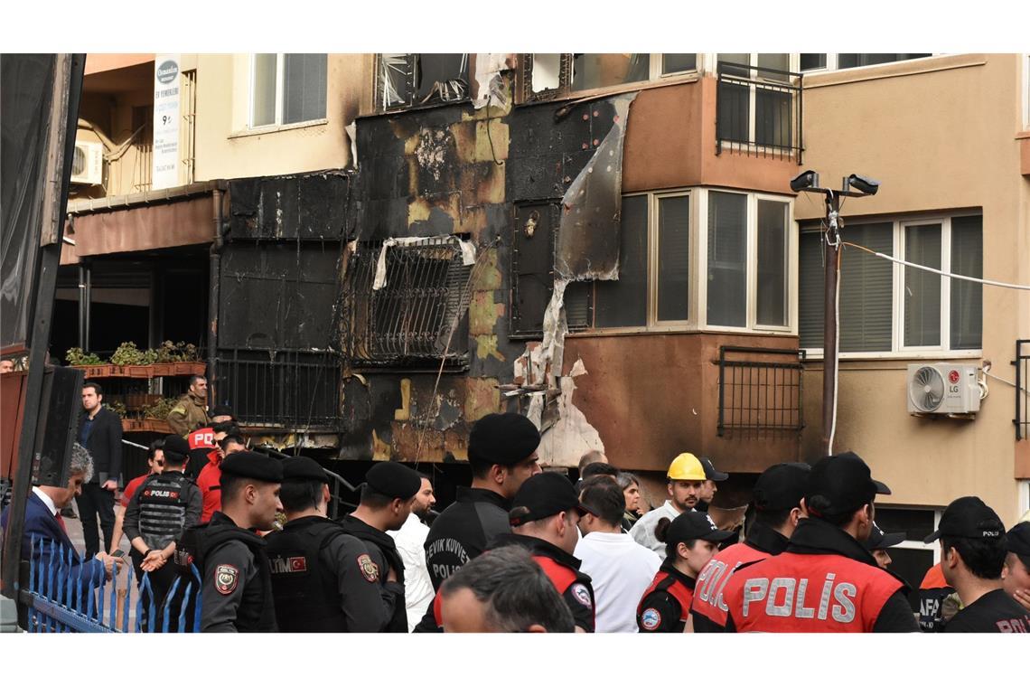 Einsatzkräfte stehen nach einem Brandausbruch vor einem teilweise verbrannten Gebäude.