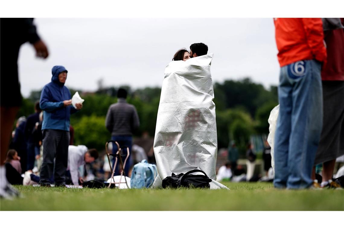 Eng umschlungen steht ein Paar in der Warteschlange am zweiten Tag der Wimbledon Championships 2024 im All England Lawn Tennis and Croquet Club.