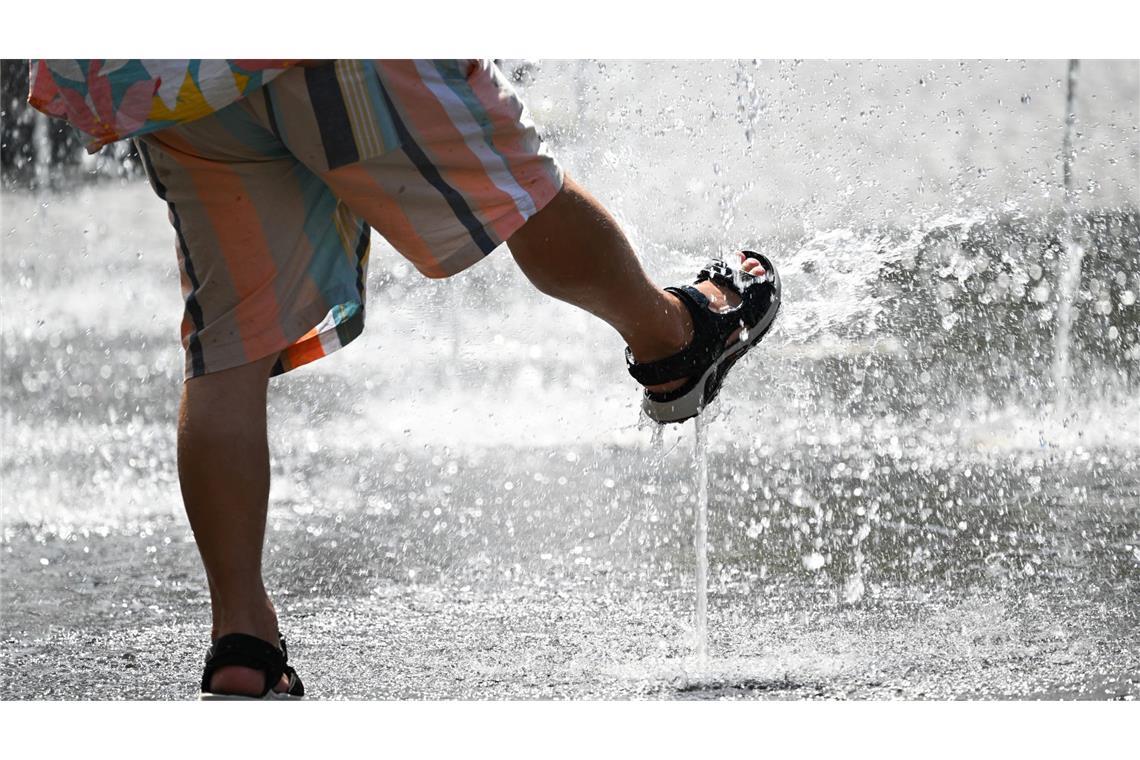 Erfrischung im Sommer. Ein Mann kühlt sich an einer Wasserfontäne ab.