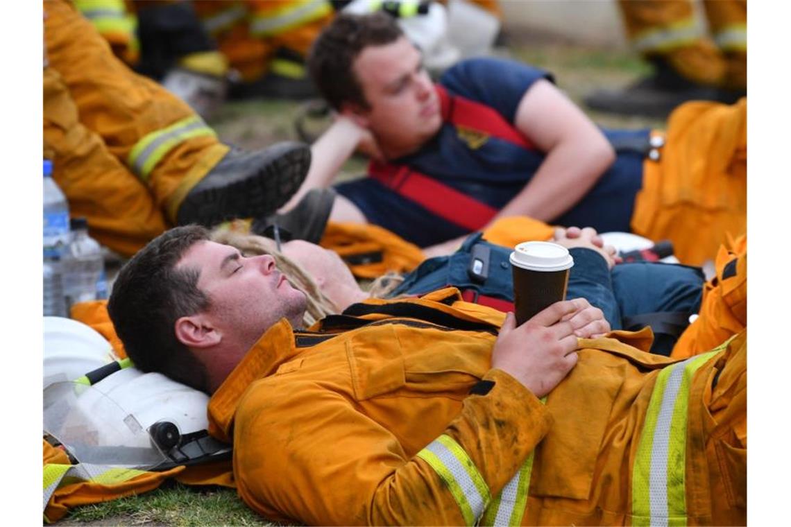 „Megafeuer“ in Australien - und die Zahl der Toten steigt Erschöpfte Feuerwehrleute ruhen sich während eines Einsatzes gegen Buschbrände bei Adelaide aus. Foto: David Mariuz/AAP/dpa