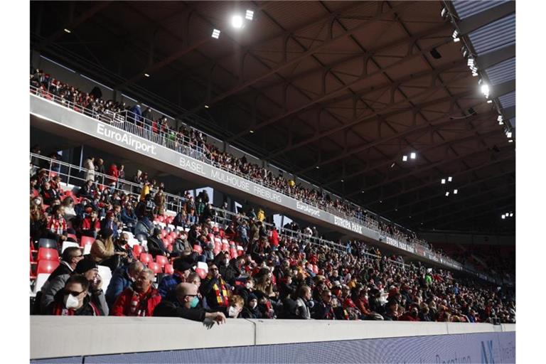 Fans des Sportclub Freiburg sitzen vor Spielbeginn auf einer der Tribünen in der Sonne. Foto: Philipp von Ditfurth/dpa