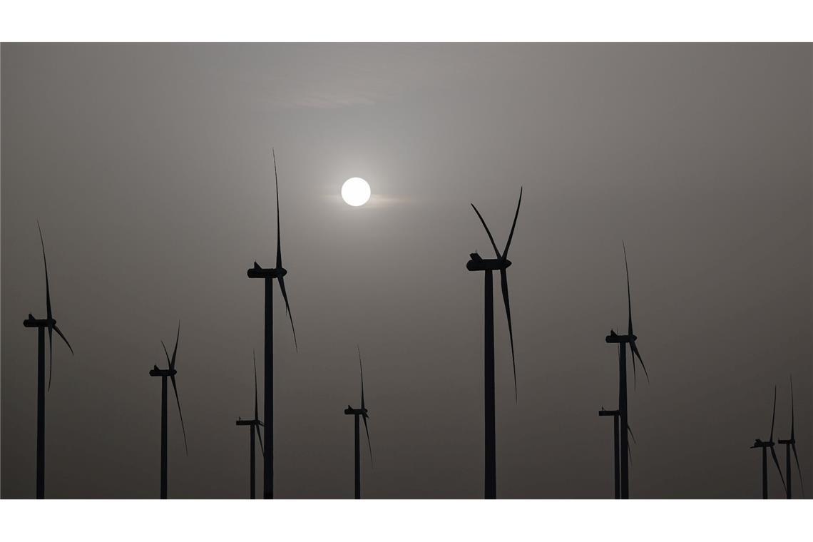 Fast schon wie ein Schwarz-Weiß-Foto wirkt diese Aufnahme vom Sonnenaufgang über einem Windenergiepark in Brandenburg. Das Wetter soll heute mit Temperaturen von bis zu 29 Grad in einigen Teilen des Landes noch einmal sommerlich werden. In der Nacht kühlt es sich dann allerdings deutlich ab.