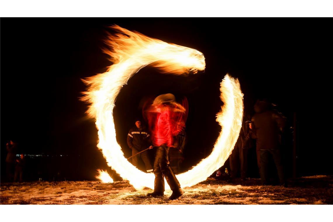 Fastnachtstradition in Bulgarien - Ein Bild mit Langzeitbelichtung zeigt einen Jungen, der mit Feuerkugeln spielt, während Ritualen zur Feier von Mesni Zagovezni (Fastnacht) im Dorf Lozen.