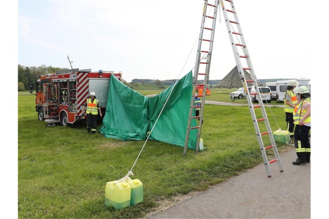 Feuerwehrleute haben auf dem Flugplatzgelände in Saulgau einen sichtschutz errichtet. Foto: Thomas Warnack