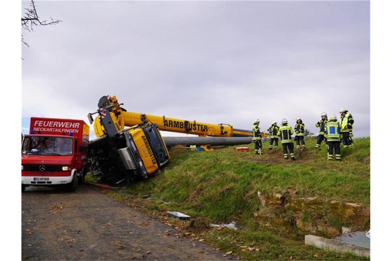 Feuerwehrleute stehen an einem umgekippten Kranwagen. Foto: Kohls/SDMG/dpa