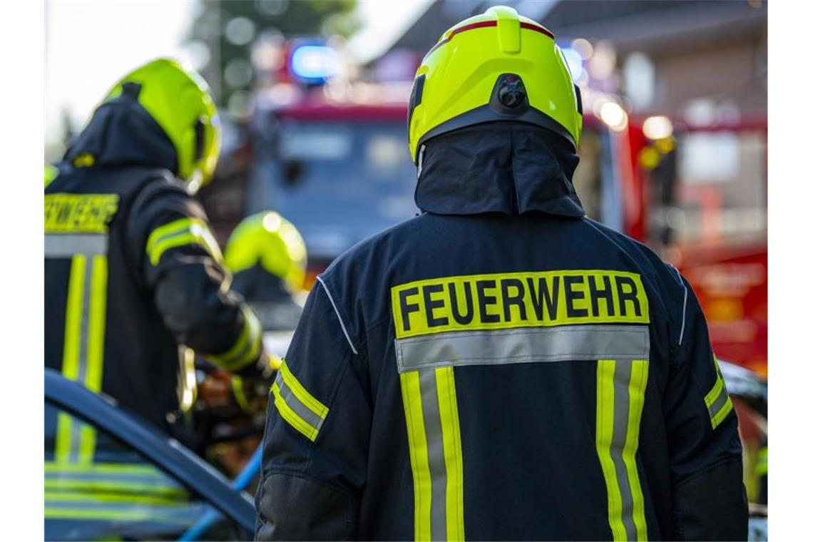 Feuerwehrleute stehen um ein Auto, das einen Unfall gehabt hat. Foto: David Inderlied/dpa/Symbolbild