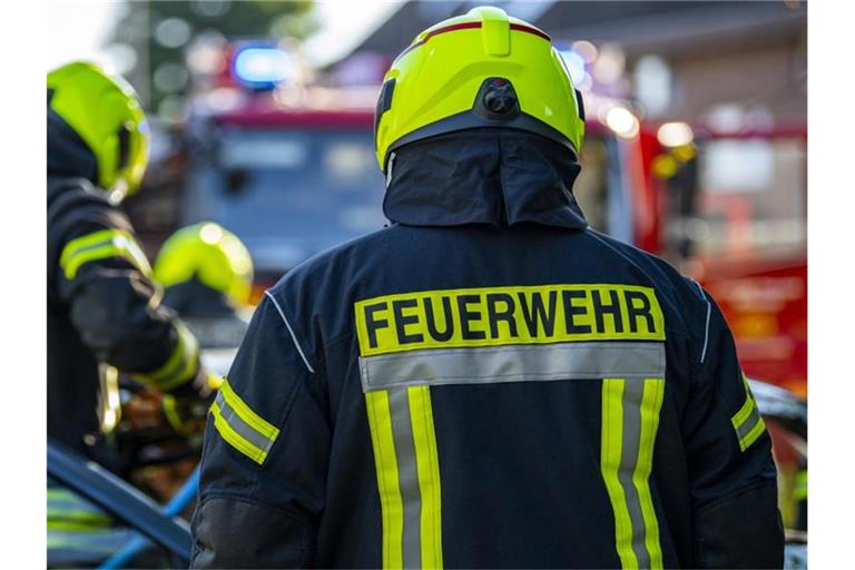 Feuerwehrleute stehen um ein Auto, das einen Unfall gehabt hat. Foto: David Inderlied/dpa/Symbolbild