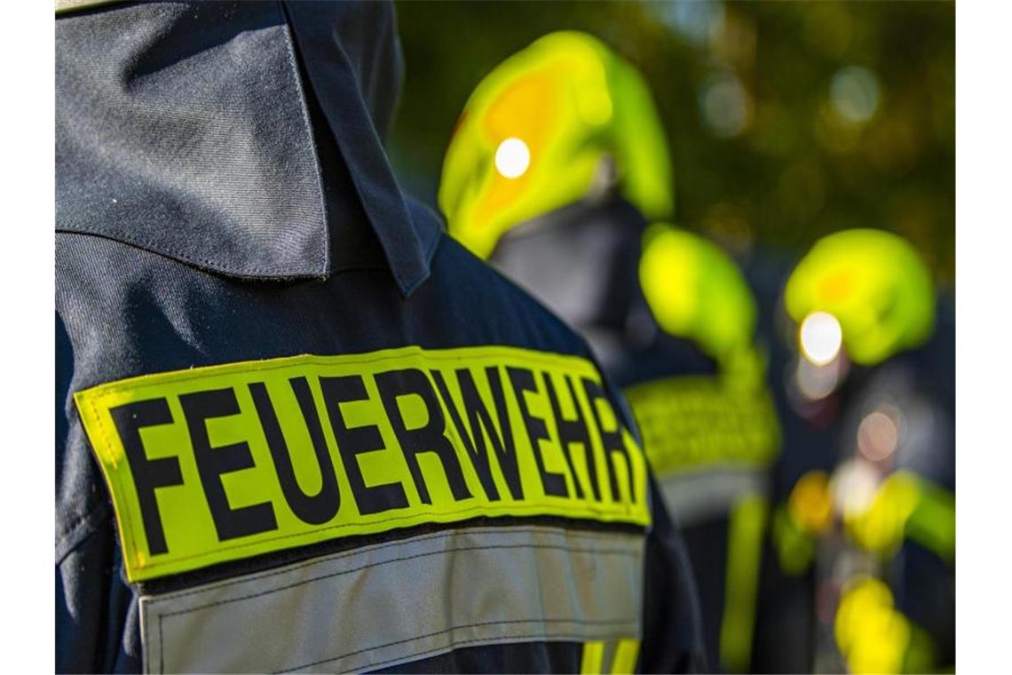 Feuerwehrleute stehen zusammen, um den Einsatz zu besprechen. Foto: David Inderlied/dpa/Symbolbild