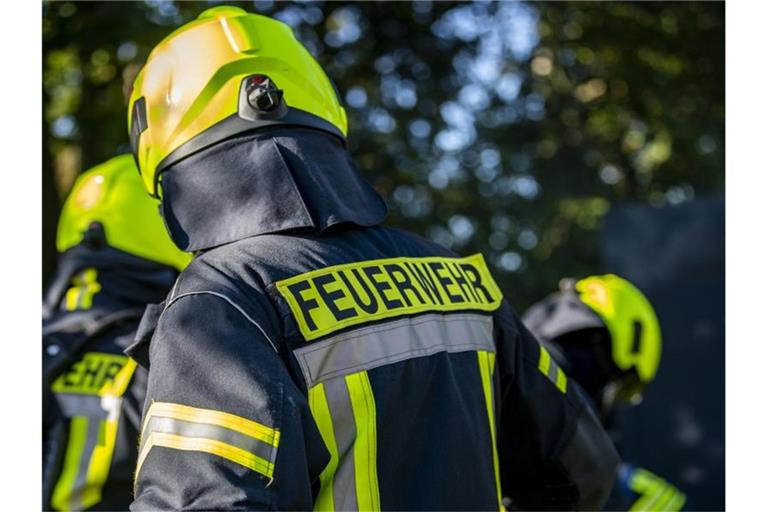 Feuerwehrleute stehen zusammen, um den Einsatz zu besprechen. Foto: David Inderlied/dpa/Symbolbild