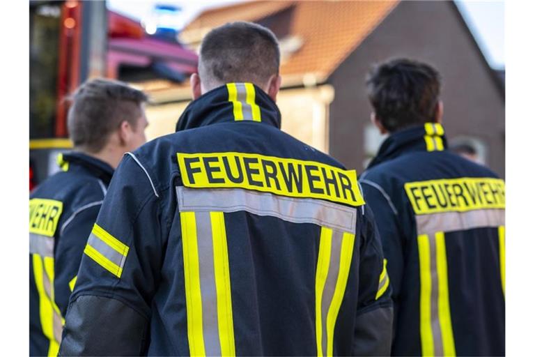 Feuerwehrleute stehen zusammen, um den Einsatz zu besprechen. Foto: David Inderlied/dpa/Symbolbild