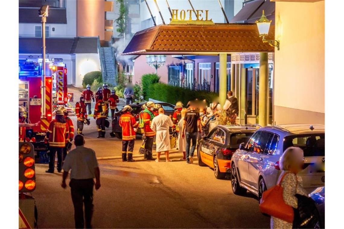 Feuerwehrleute und Hotelgäste stehen vor dem Eingang des Hotels in Ettlingen. Foto: Aaron Klewer/Einsatz-Report24/dpa