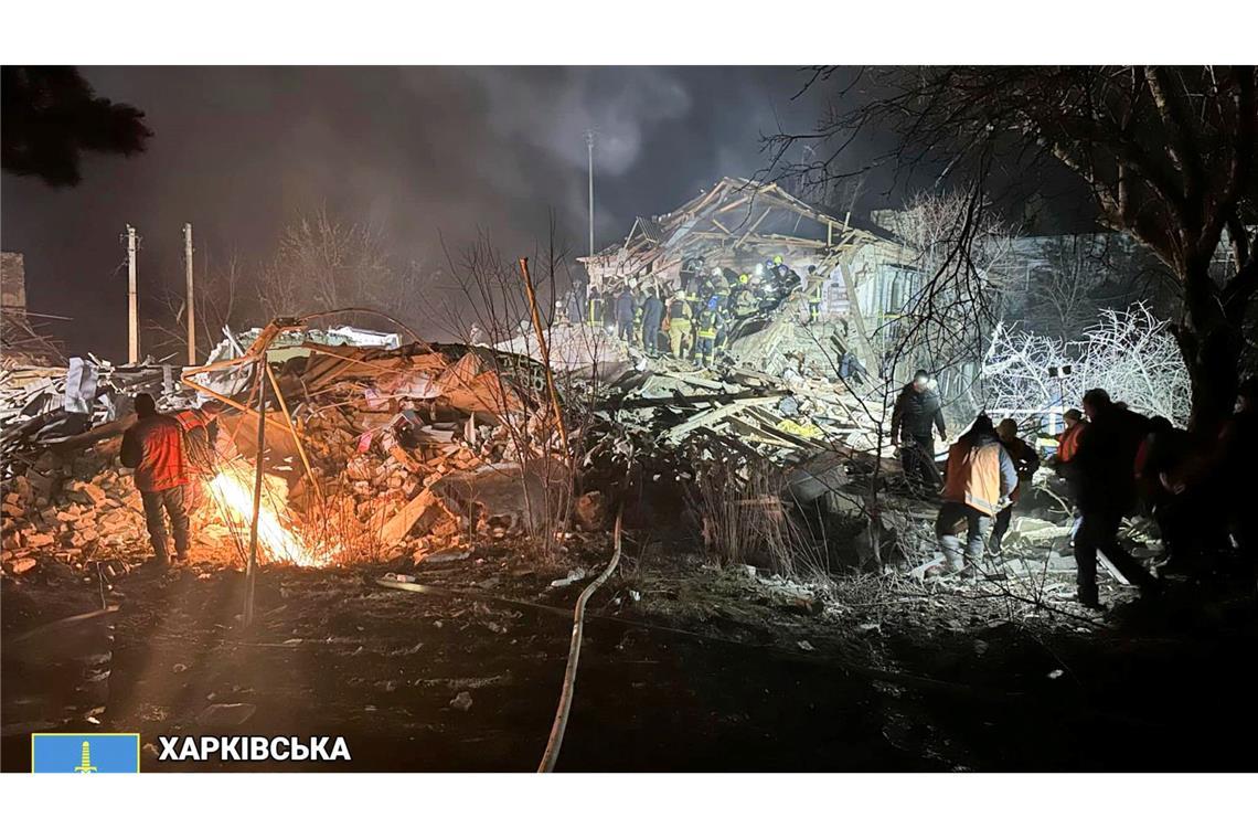 Feuerwehrleute untersuchen in der Region Charkiw die Trümmer eines zerstörten Wohnhauses.