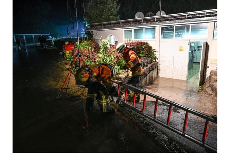 Feuerwehrmänner verlegen einen Schlauch, um einen Keller auszupumpen. Foto: Felix Kästle/dpa/Symbolbild