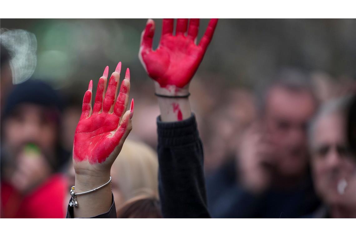 Frauen heben während einer Demonstration in Novi Sad ihre rot bemalten Hände.