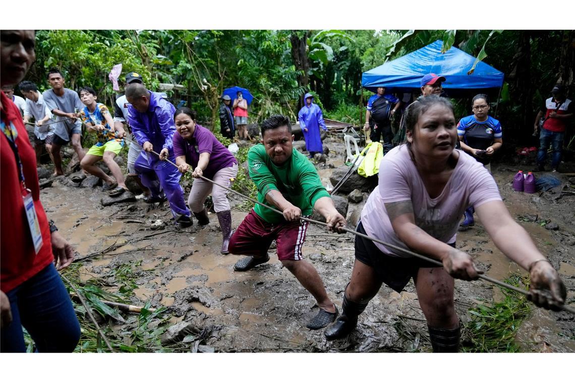 Freiwillige Helfer und Retter ziehen an einem Strang, während sie nach einem Erdrutsch auf den Philippinen nach Vermissten suchen.