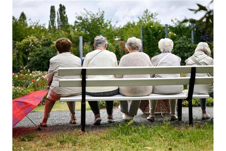 Fünf ältere Frauen machen nach einem Regenschauer eine Pause auf einer Parkbank. Foto: Frank May/dpa