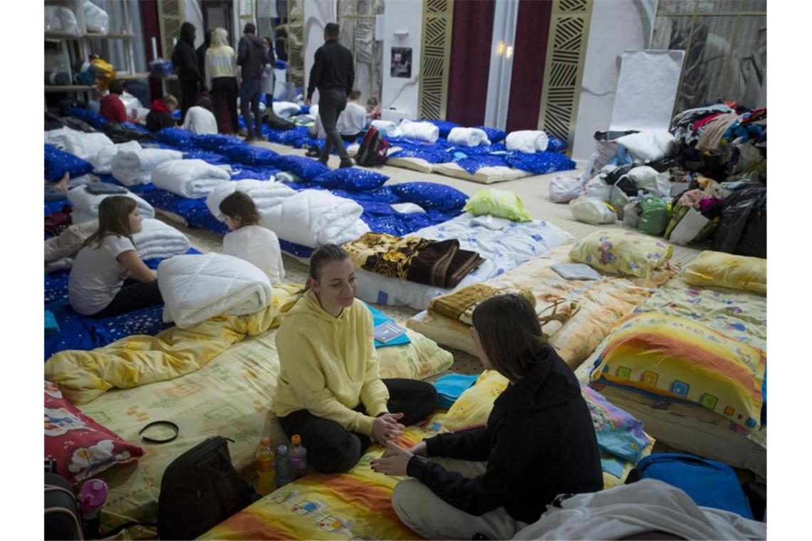 Geflüchtete Menschen aus der Ukraine sitzen in der Veranstaltungshalle eines Hotels im rumänischen Siret. Foto: Alexandru Dobre/AP/dpa